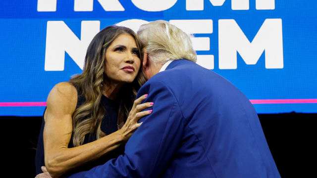 A photo of Kristi Noem embracing Donald Trump onstage at a rally.