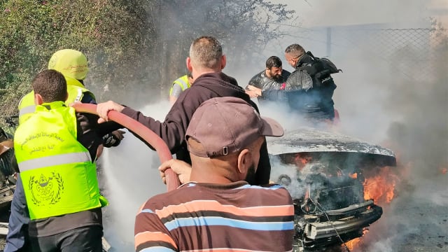 Firefighters douse a burning car after it was hit in an Israeli strike in Lebanon's southern area of Tyre.