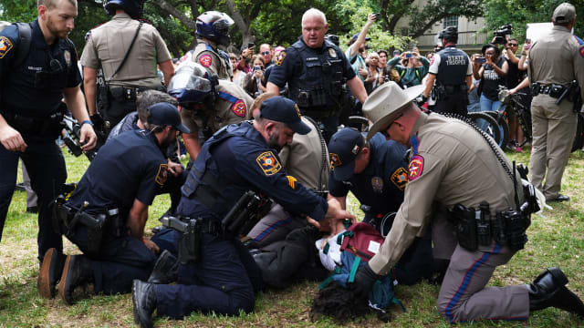 A photo including a student being detained by police on the campus of the University of Texas in Austin