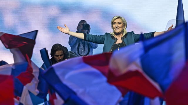 Marine Le Pen gestures to a crowd waving French flags