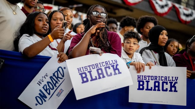 Members of the audience hold signs that read "We're On Board" and "Historically Black" before the start of a campaign rally for Joe Biden and Kamala Harris at Girard College on May 29, 2024 in Philadelphia, Pennsylvania.