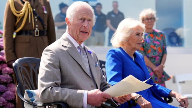 King Charles III makes a statement to members of the Alderney island with Britain's Queen Camilla.