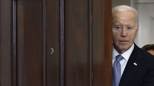 President Biden peeks out from behind a door before delivering remarks at the White House. 