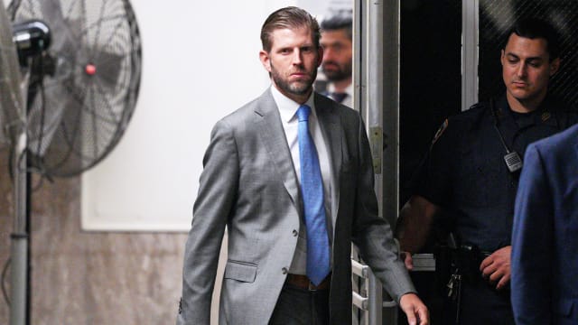 Eric Trump, wearing a suit, exits a New York City courthouse.
