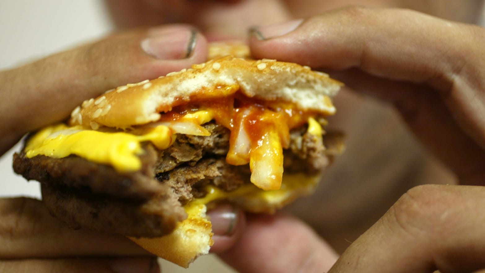 A close-up photo of a man’s hands holding a Big Mac, about to take a bite.