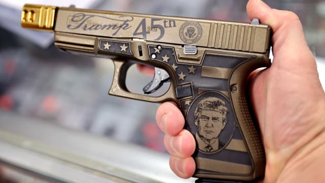 A worker shows off Glock 19 Donald Trump commemorative 9mm pistol being offered for sale at Freddie Bear Sports on April 08, 2021 in Tinley Park, Illinois.