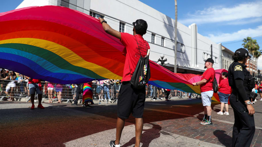 A group holds a rainbow flag while celebrating during the Tampa Pride Parade.