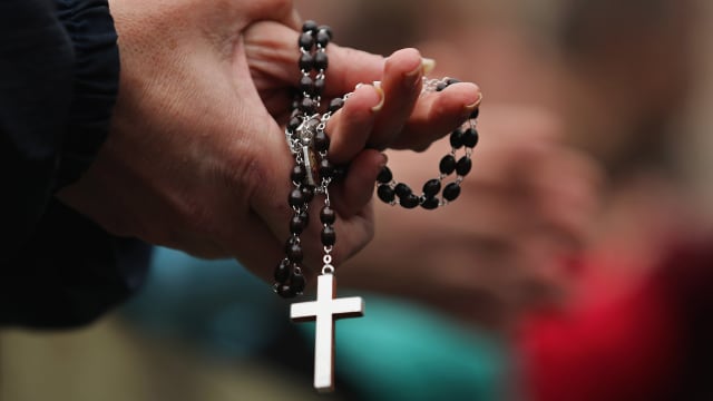 A woman holds rosary beads