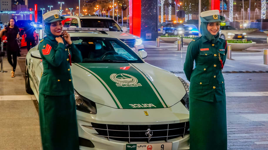 Dubai police officers stand beside a Ferrari police cruiser.