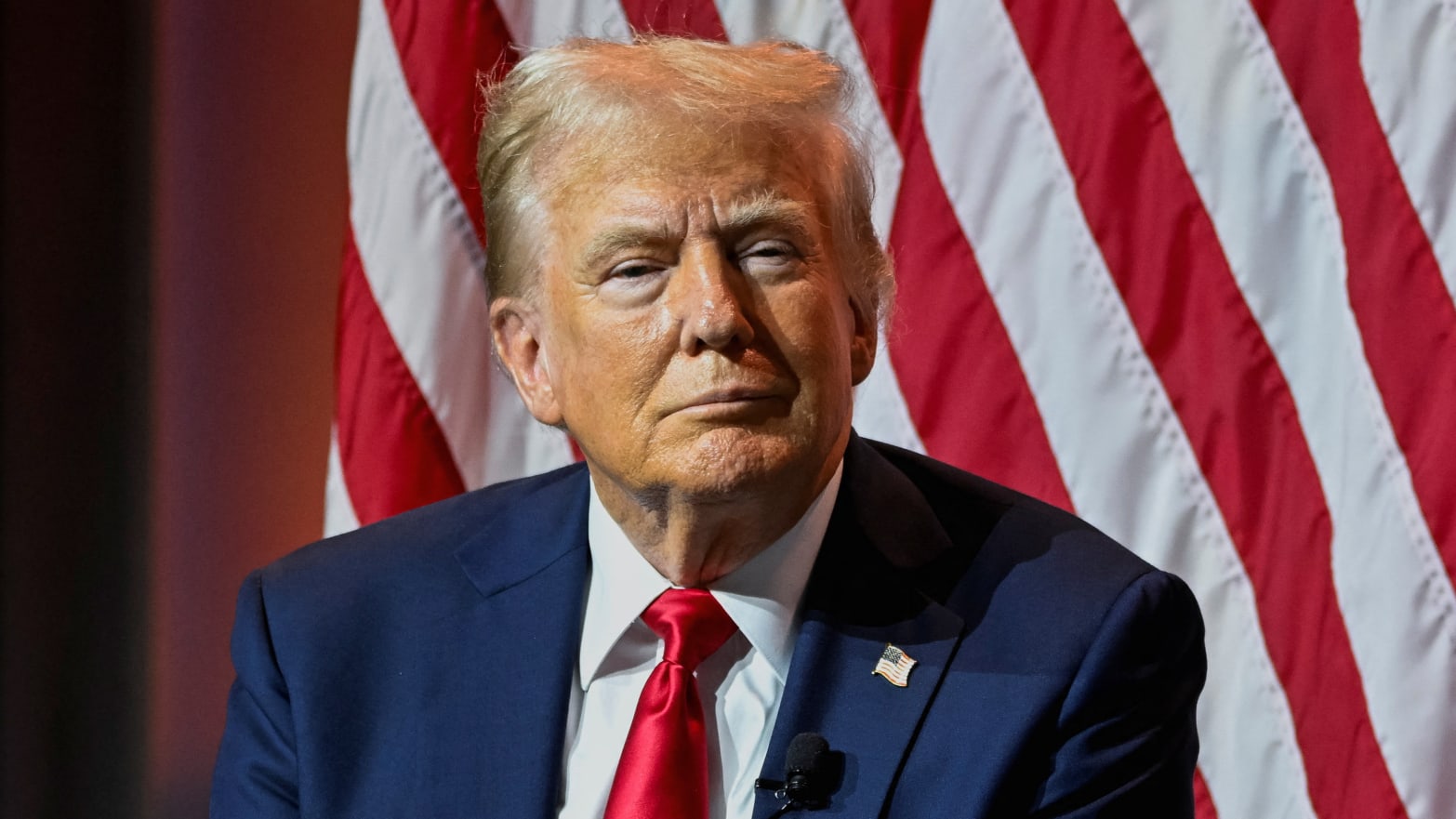 Donald Trump stares forward while seated on stage