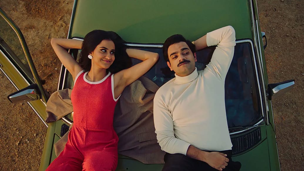 A picture of Amrit Kaur and Hamza Haq laying on the hood of a car in 'The Queen of my Dreams'