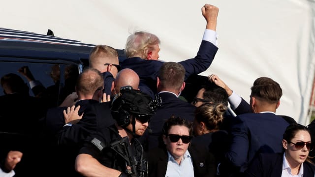 Republican presidential candidate and former U.S. President Donald Trump gestures as he gets into a vehicle with the assistance of U.S. Secret Service personnel .