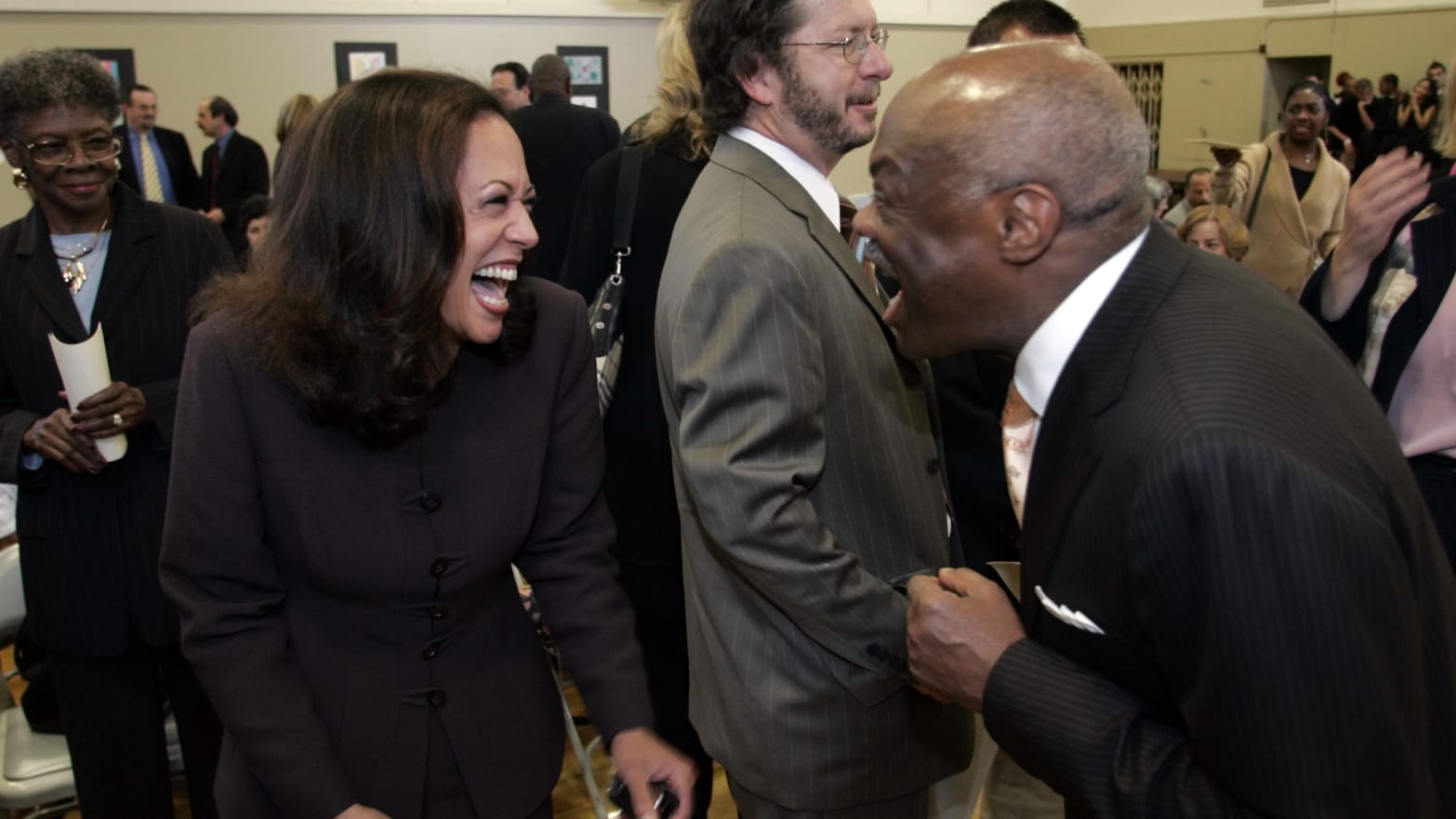 Kamala Harris facing Willie Brown in a crowd, both laughing