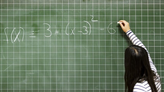 Girl solves math problem on a chalkboard