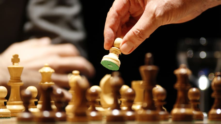 A male hand holds a chess piece over a board