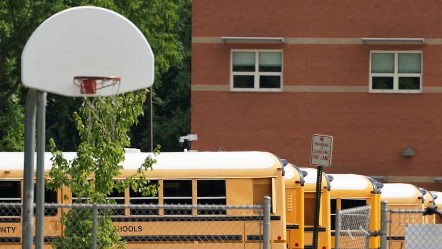 An outdoor school basketball court near school buses