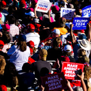 A crowd holds signs as Republican presidential candidate, former U.S. President Donald Trump speaks during a rally on May 1, 2024 in Michigan.