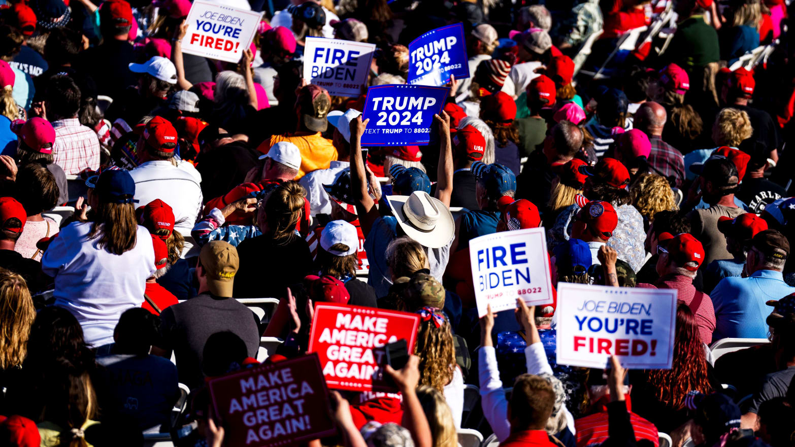 A crowd holds signs as Republican presidential candidate, former U.S. President Donald Trump speaks during a rally on May 1, 2024 in Michigan.