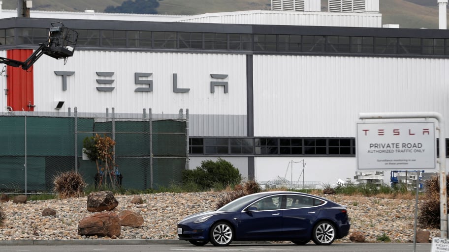 A Tesla vehicle drives past a Tesla factory in California.