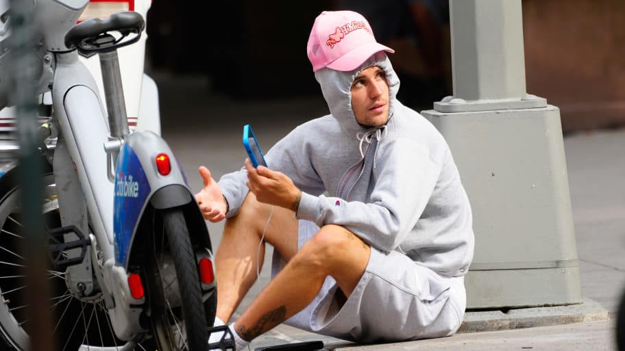 Justin Bieber is seen sitting on the sidewalk.