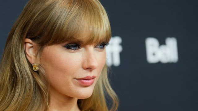 Taylor Swift stares forward while posing for photos outside an event.