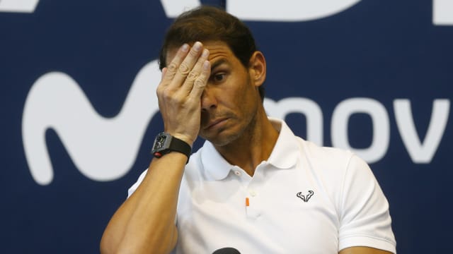 Rafael Nadal puts a hand over his face during a press conference.