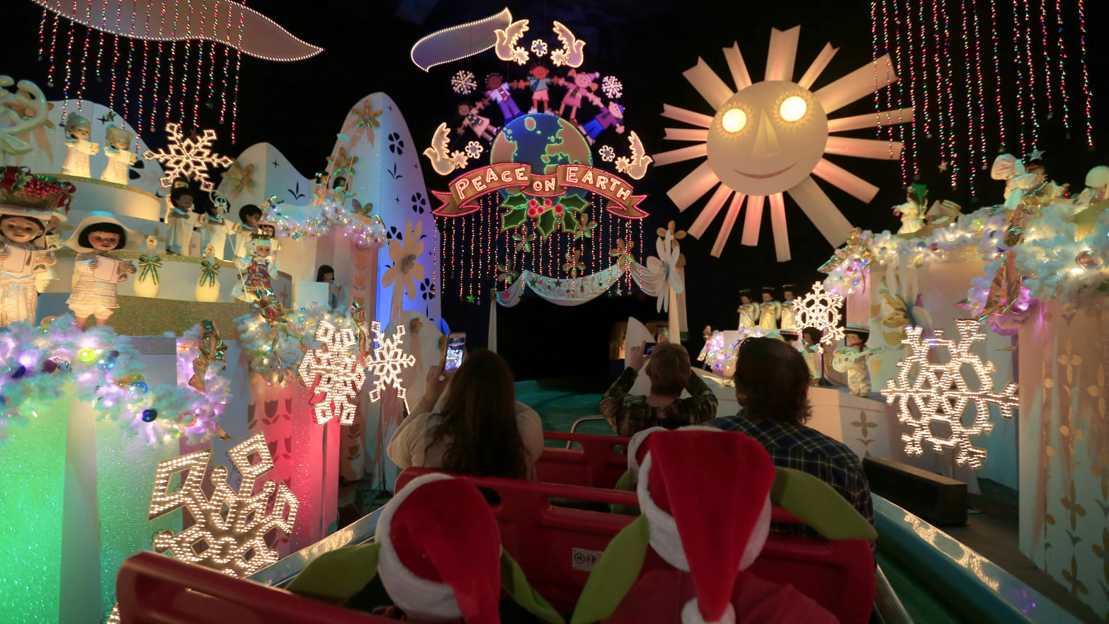 Guests take a boat ride through \"It's a Small World\" ride decorated for the holiday season during the Star Wars Season of The Force at Disneyland