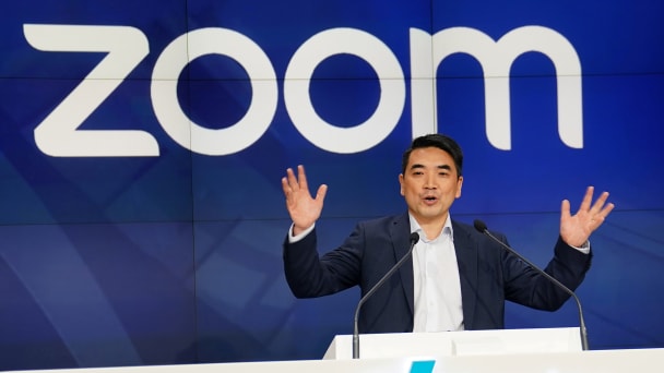 Zoom CEO Eric Yuan speaks in front of a sign displaying the company logo