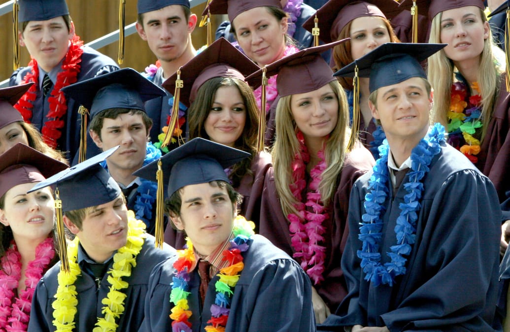 Adam Brody, Rachel Bilson, Mischa Barton, and Benjamin McKenzie in graduation caps and gowns in a still from 'The OC'