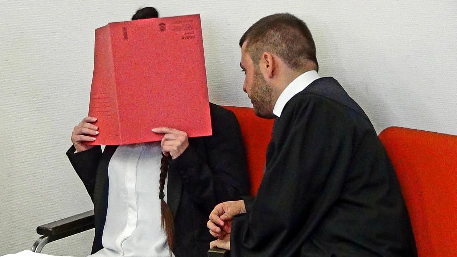 Defendant Jennifer W. covers her face as she waits for the start of the trial beside her lawyer Ali Aydin in Munich, Germany, April 9, 2019.