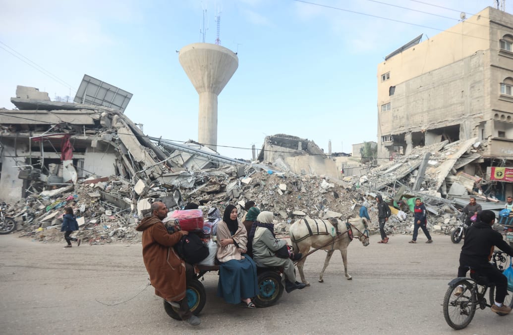 Ein Bild von Palästinensern, die durch die Trümmer in Gaza gehen.