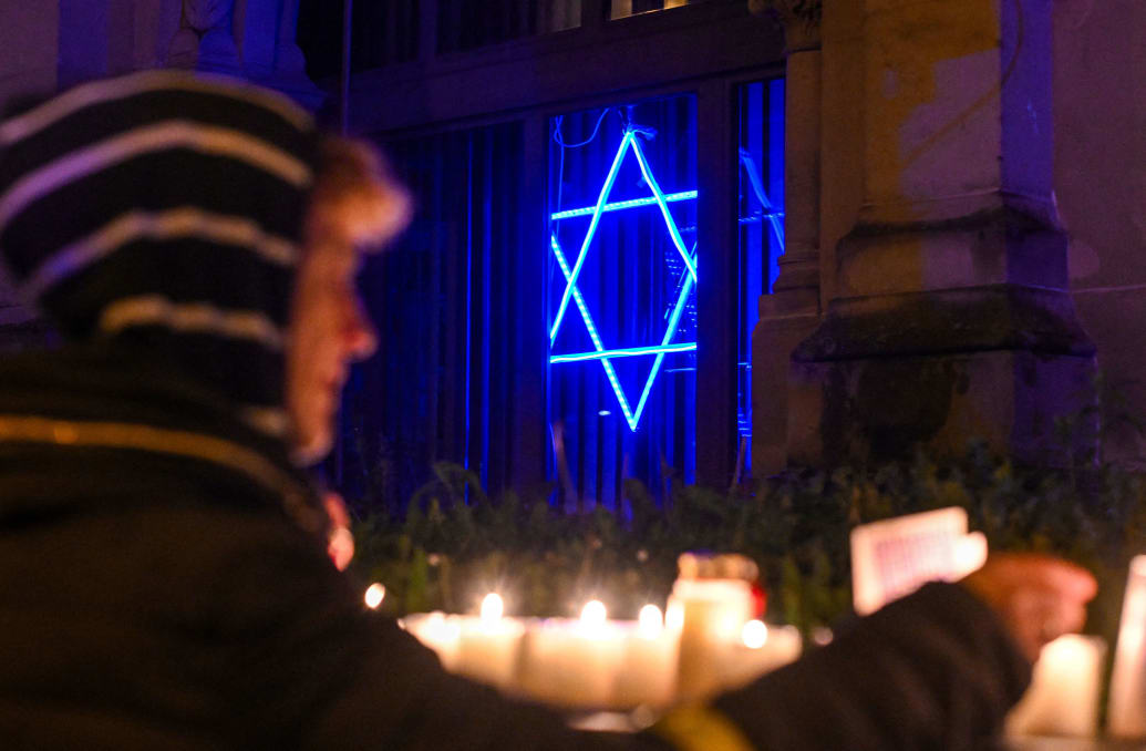 A woman lights a candle at a synagogue