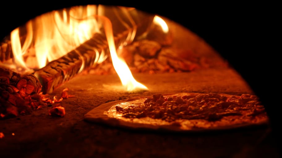 Pizza Margherita is prepared in a wood-fired oven.
