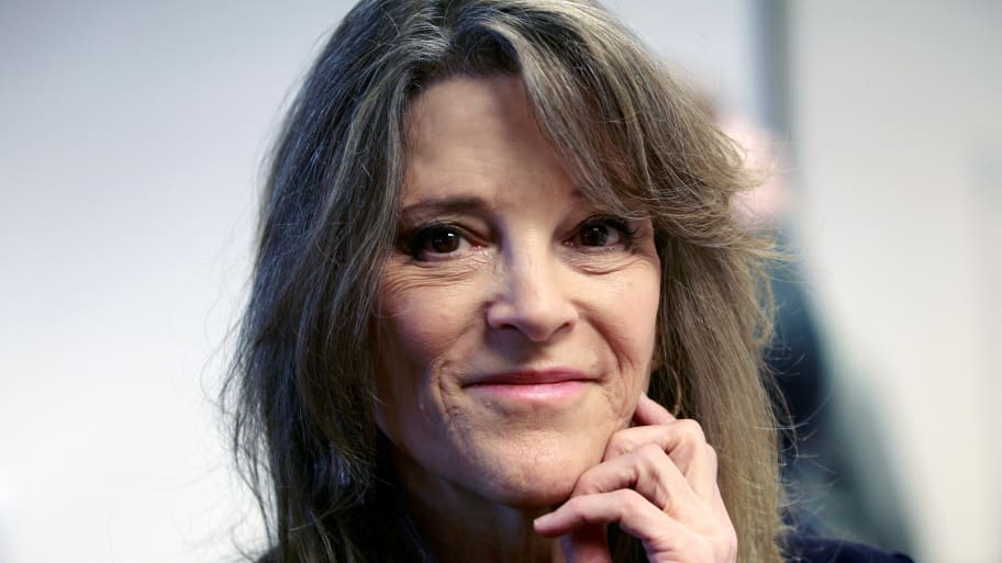 Marianne Williamson smiles with her hand on her chin