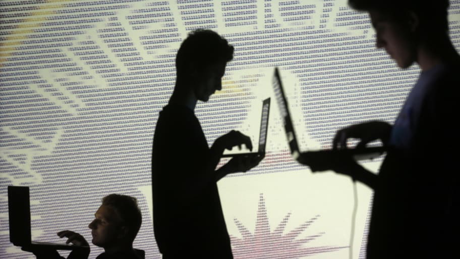 People are silhouetted as they pose with laptops in front of a screen projected with binary code and a Central Inteligence Agency (CIA) emblem, in this picture illustration taken in Zenica