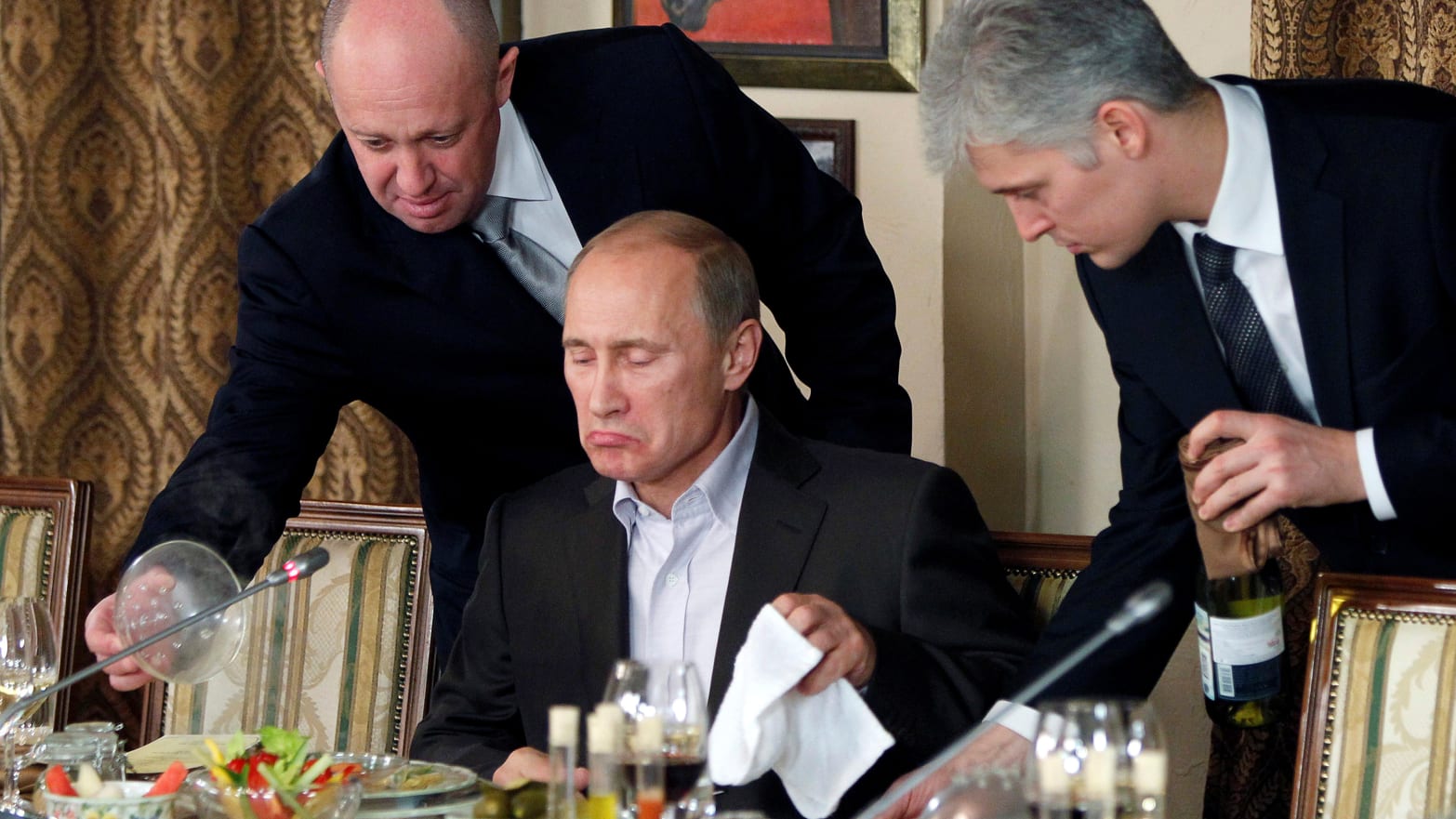 Yevgeny Prigozhin, left, assists Russian Prime Minister Vladimir Putin during a 2011 dinner 