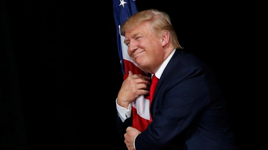 Donald Trump hugs a U.S. flag as he comes onstage to rally with supporters in Tampa, Florida, Oct. 24, 2016. 