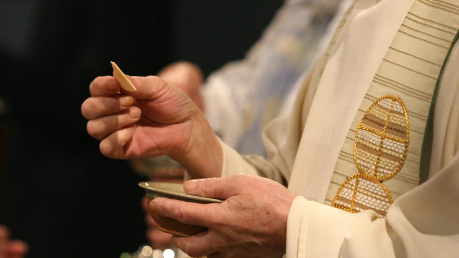 a priest giving communion wafers 