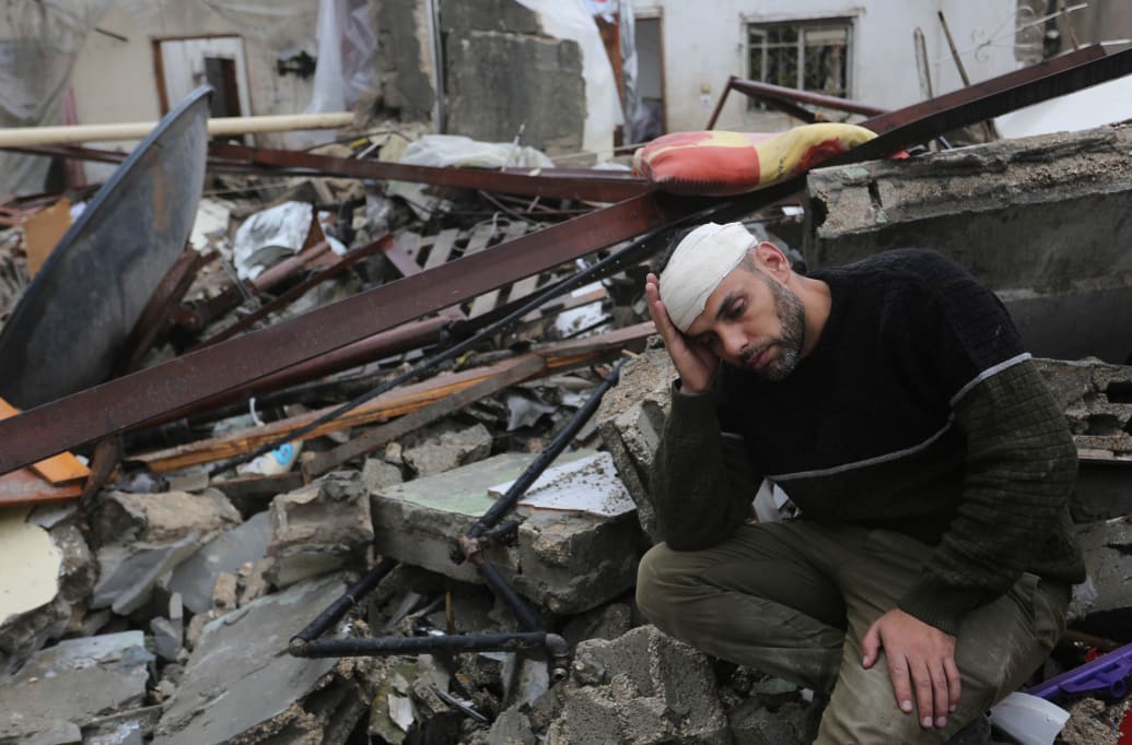 A man sits on the rubble of a building that has been destroyed in an Israeli airstrike in Gaza. 