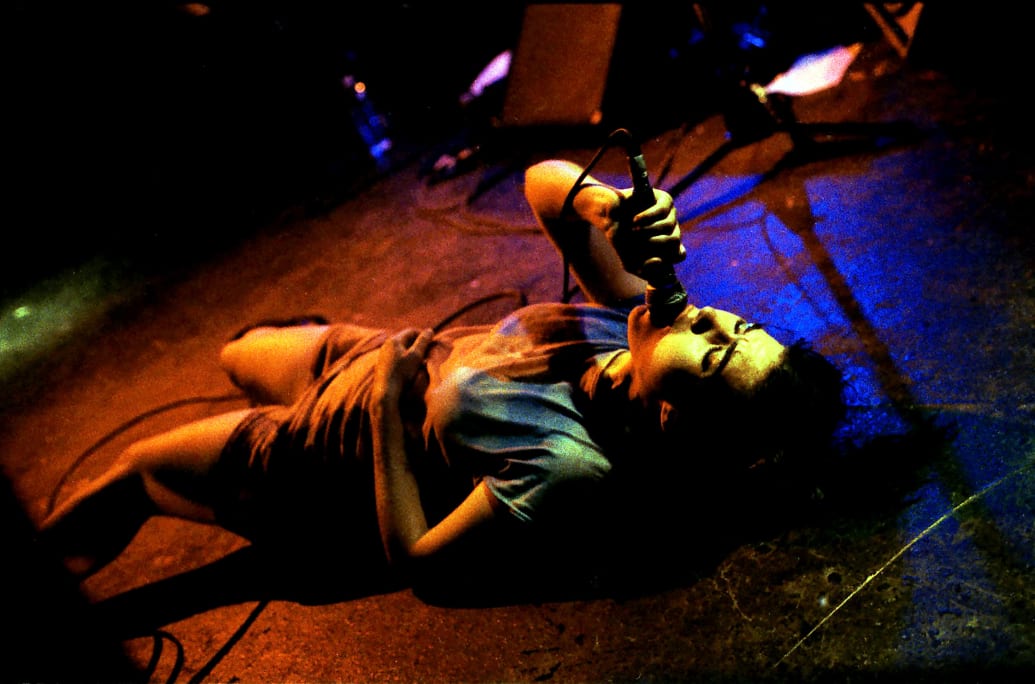 Kathleen Hanna lays on her back and sings. 