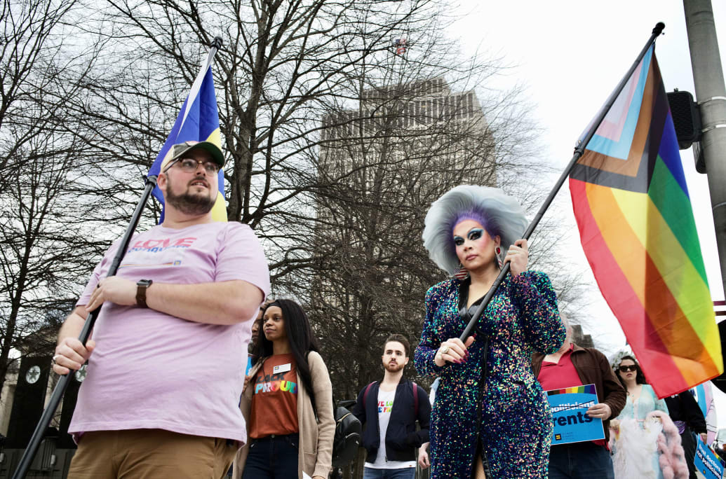 A photograph of Drag Performer Vidalia Anne Gentry holding a Pride flag a rally on February 14, 2023 in opposition to the SB3/HB9 bill that would prohibit drag performances in public.