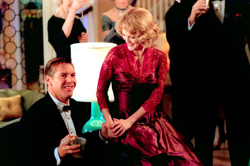 Dennis Quaid holds on to a cocktail and cigarette while he sits on a couch with Julianne looking at him in a still from 'Far From Heaven'