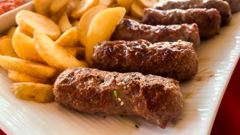 Traditional balkan grilled meat called cevapcici is seen on a restaurant table