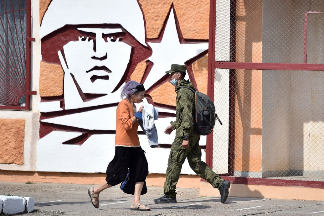 A soldier and a woman walk past the headquarters of the Operative Group of the Russian Troops in the town of Tiraspol, the capital of Transnistria - Moldova's pro-Russian breakaway region on the eastern border with Ukraine.