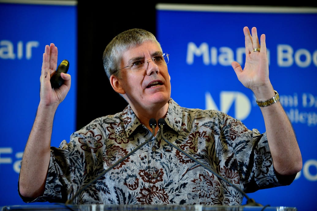 Rick Riordan speaks in front of a dias at an event. 