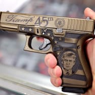 A worker shows off Glock 19 Donald Trump commemorative 9mm pistol being offered for sale at Freddie Bear Sports on April 08, 2021 in Tinley Park, Illinois.