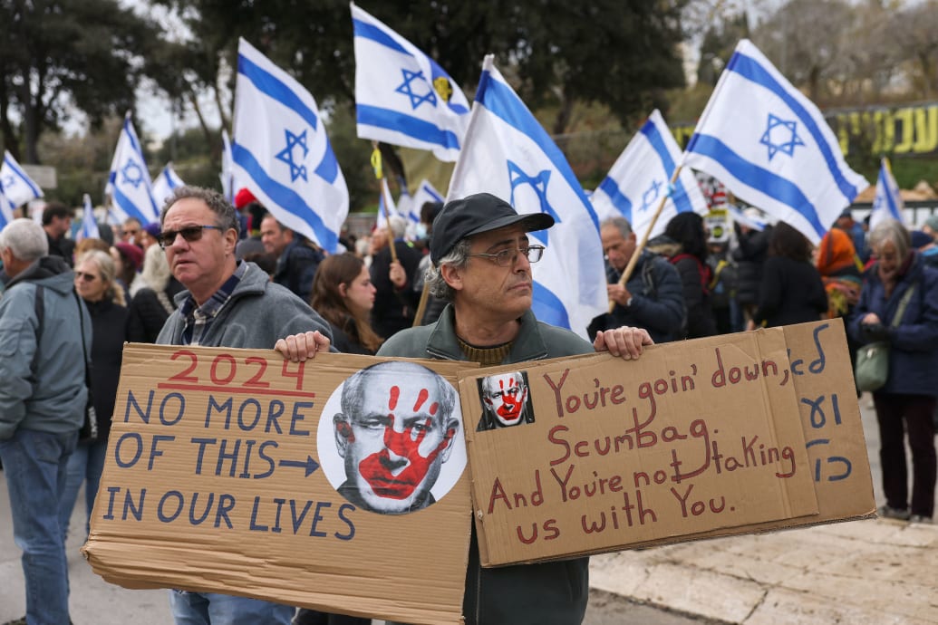 A protester lifts placards against Israeli Prime Minister Benjamin Natanyahu during a rally demanding the release of Israelis taken hostage a hundred days earlier by the Palestinian Hamas movement on October 7