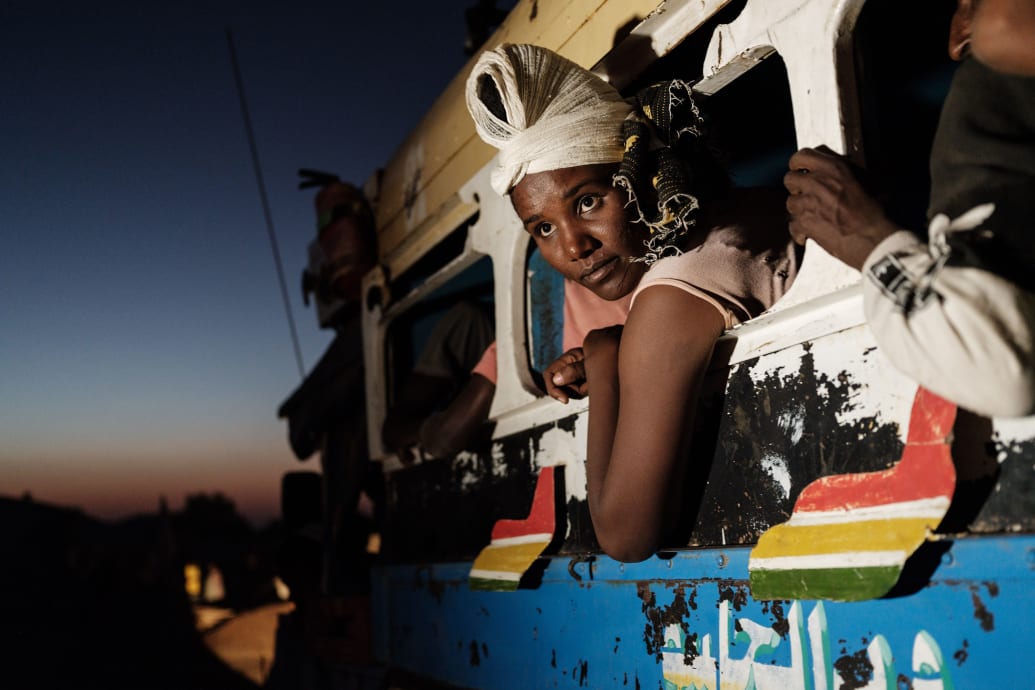 An Ethiopian  woman hangs out of a bus and looks back as it arrives near the Ethiopian border.