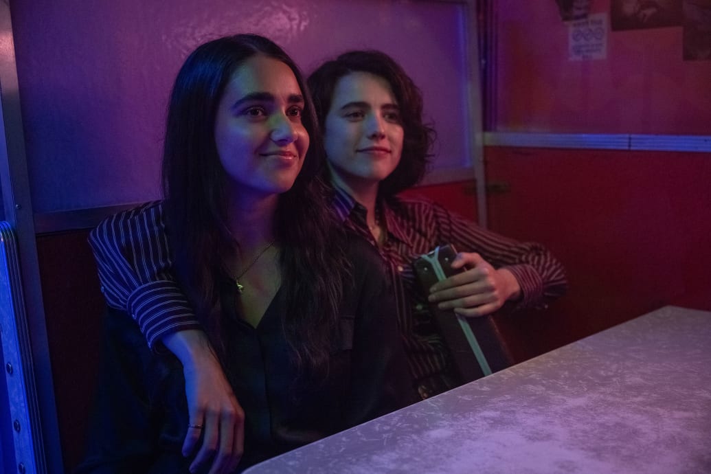 Margaret Qualley and Geraldine Viswanathan sit in a restaurant booth in a still from ‘Drive Away Dolls’