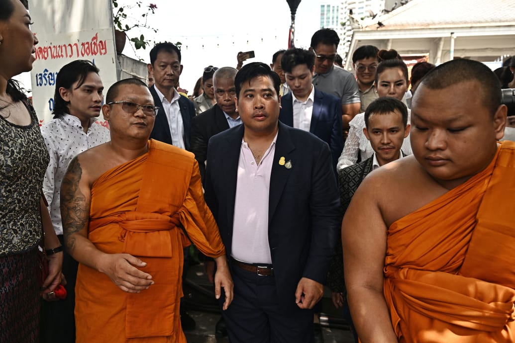 Vacharaesorn Vivacharawongse walks next to monks and people in Thailand.